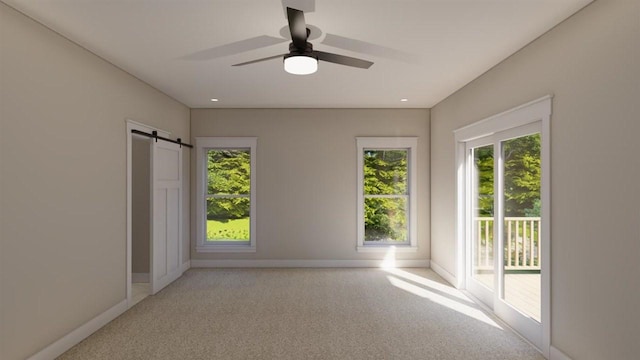 carpeted spare room featuring a barn door and ceiling fan