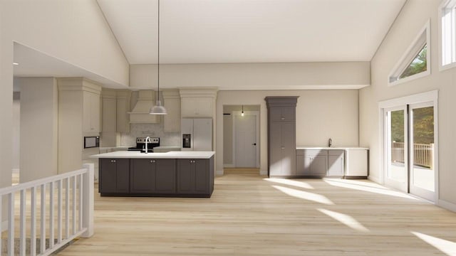 kitchen featuring pendant lighting, light wood-type flooring, white fridge with ice dispenser, and an island with sink