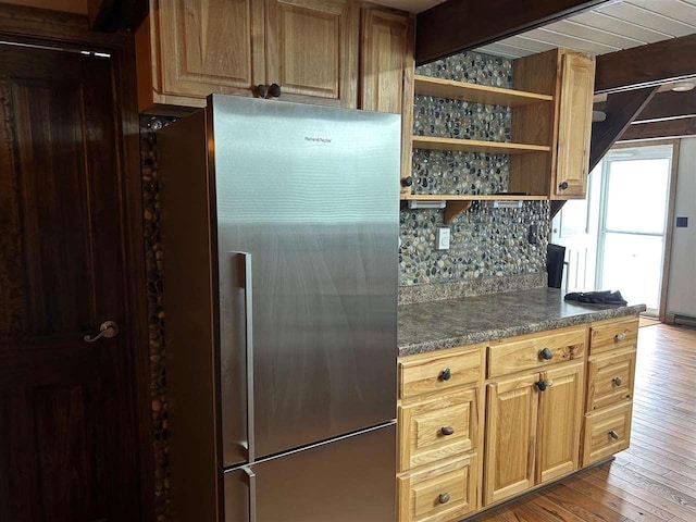 kitchen featuring hardwood / wood-style flooring, backsplash, stainless steel fridge, and beam ceiling