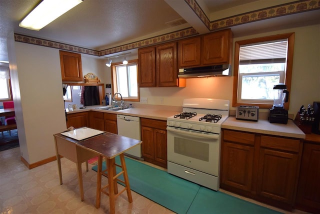 kitchen with beamed ceiling, white appliances, a wealth of natural light, and sink