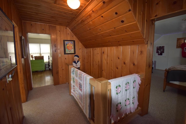 interior space featuring wooden ceiling, light carpet, wooden walls, and vaulted ceiling