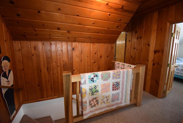 additional living space with light carpet, vaulted ceiling, and wooden walls