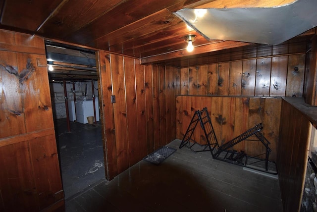 basement featuring wooden walls and independent washer and dryer