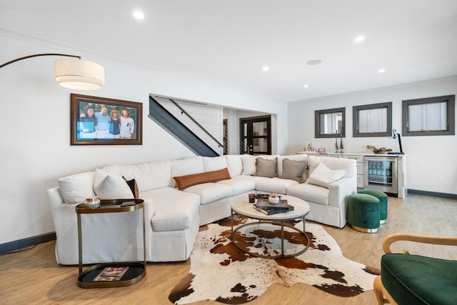 living room with crown molding, light hardwood / wood-style flooring, and beverage cooler