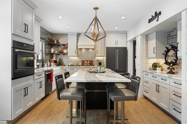 kitchen with a center island, light hardwood / wood-style flooring, a kitchen bar, custom range hood, and stainless steel appliances