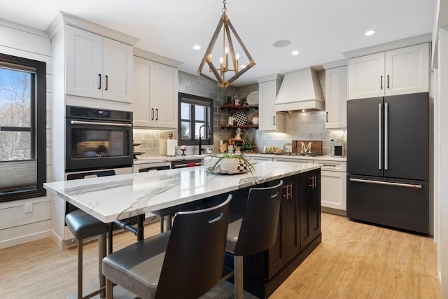 kitchen with premium range hood, white cabinetry, hanging light fixtures, and stainless steel appliances