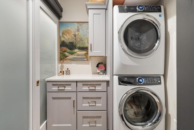 washroom with cabinets and stacked washing maching and dryer