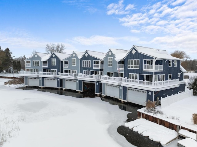 snow covered back of property featuring a balcony