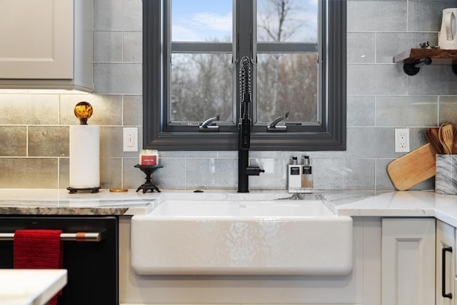 interior details with tasteful backsplash, white cabinetry, and sink