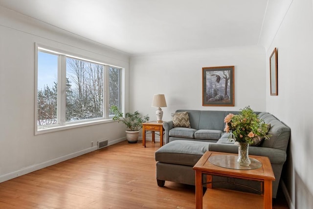 living room featuring plenty of natural light, ornamental molding, and light wood-type flooring