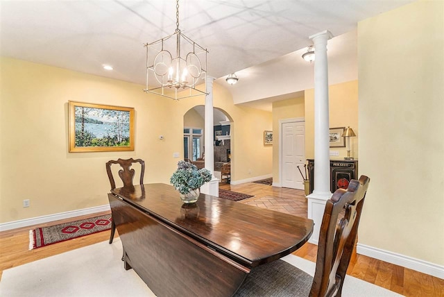 dining room featuring decorative columns, light hardwood / wood-style flooring, and an inviting chandelier