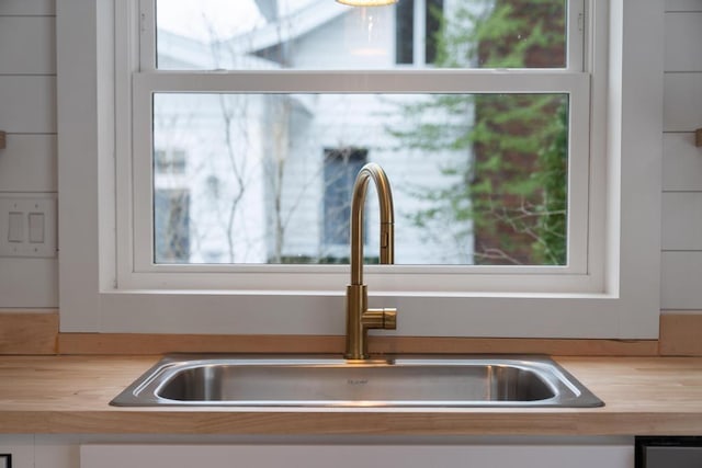 details with white cabinetry, sink, and wood counters