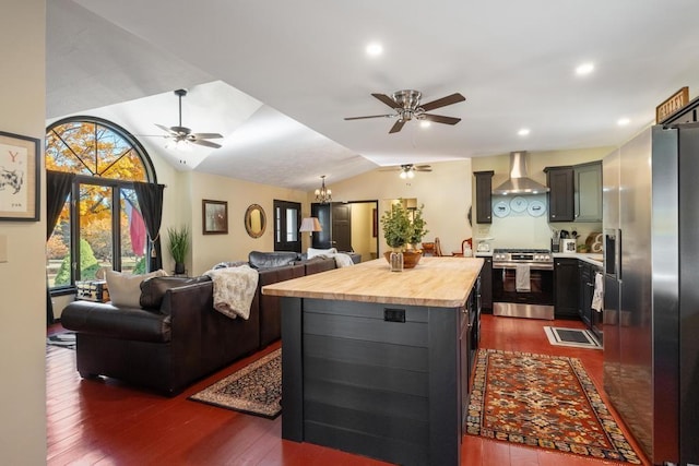 kitchen featuring lofted ceiling, wall chimney range hood, appliances with stainless steel finishes, a kitchen island, and dark hardwood / wood-style flooring