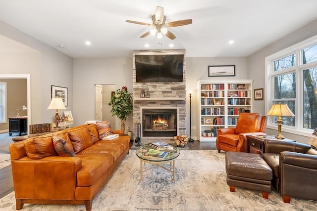 living room with ceiling fan, wood-type flooring, and a tile fireplace