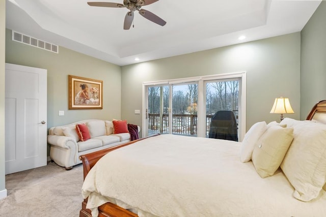 carpeted bedroom with a tray ceiling, access to exterior, and ceiling fan