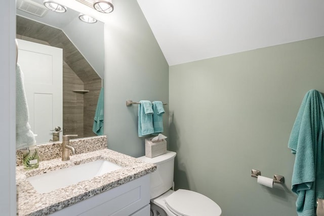 bathroom with vanity, toilet, and lofted ceiling