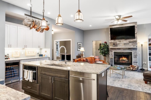 kitchen featuring white cabinetry, sink, hanging light fixtures, beverage cooler, and a fireplace