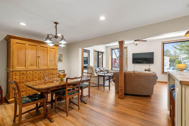 dining space featuring decorative columns, light hardwood / wood-style flooring, and a chandelier