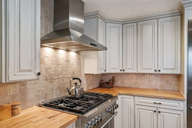 kitchen with high end range, wall chimney range hood, backsplash, and wooden counters