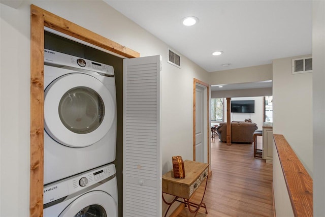 washroom with stacked washing maching and dryer and wood-type flooring