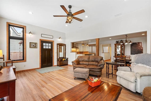 living room with ceiling fan with notable chandelier and light hardwood / wood-style floors