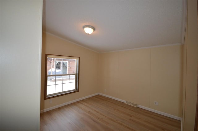 spare room featuring light hardwood / wood-style floors and lofted ceiling