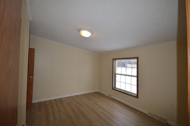 spare room featuring ornamental molding, a textured ceiling, and light hardwood / wood-style flooring