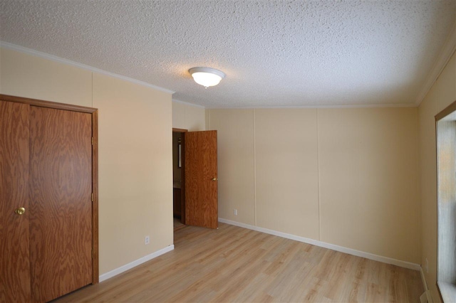 spare room with a textured ceiling, light hardwood / wood-style floors, and crown molding