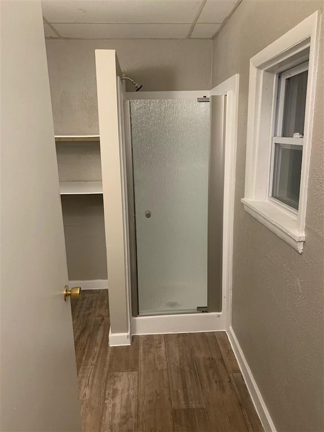 bathroom with a paneled ceiling, an enclosed shower, and wood-type flooring