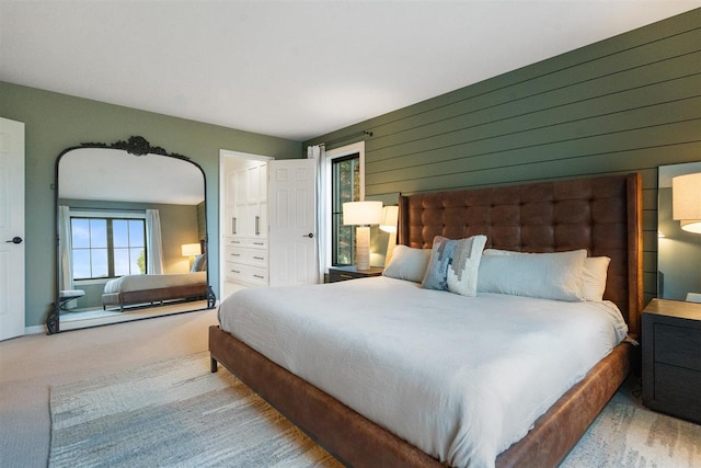 bedroom featuring light carpet and wooden walls