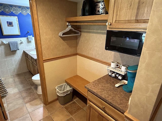 bathroom with vanity, tile walls, and toilet