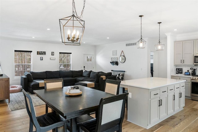 dining space with a notable chandelier, light wood-type flooring, and ornamental molding