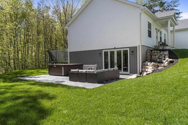 back of property featuring outdoor lounge area, a lawn, a trampoline, a patio area, and a hot tub