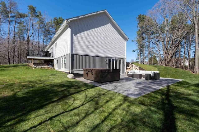 back of property with an outdoor living space, a patio, a hot tub, and a lawn