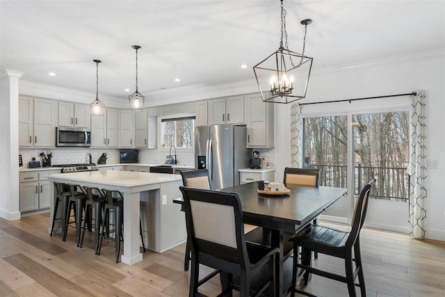 kitchen with stainless steel appliances, light hardwood / wood-style flooring, gray cabinets, a kitchen island, and hanging light fixtures