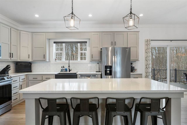 kitchen with gray cabinetry, a center island, backsplash, sink, and stainless steel appliances