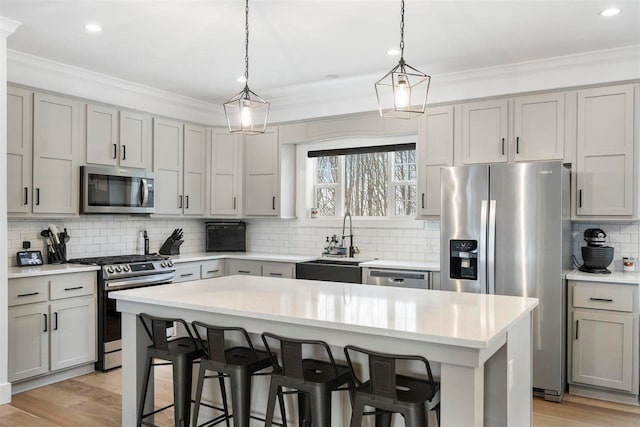 kitchen with gray cabinets, decorative light fixtures, a kitchen island, and appliances with stainless steel finishes