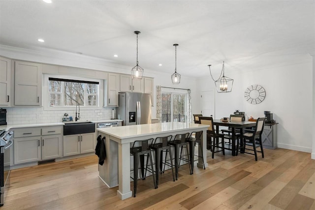 kitchen featuring gray cabinetry, a center island, sink, hanging light fixtures, and stainless steel appliances