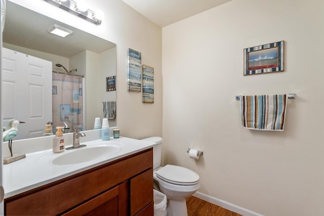 bathroom featuring hardwood / wood-style floors, vanity, toilet, and curtained shower