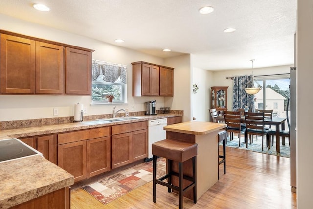 kitchen with dishwasher, a kitchen breakfast bar, sink, hanging light fixtures, and a kitchen island