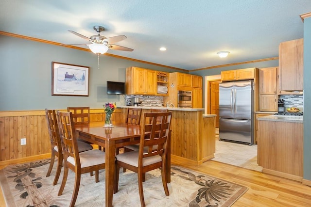 dining area with light wood-type flooring, ceiling fan, and ornamental molding