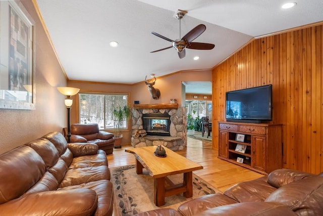 living room with lofted ceiling, crown molding, ceiling fan, a fireplace, and light hardwood / wood-style floors