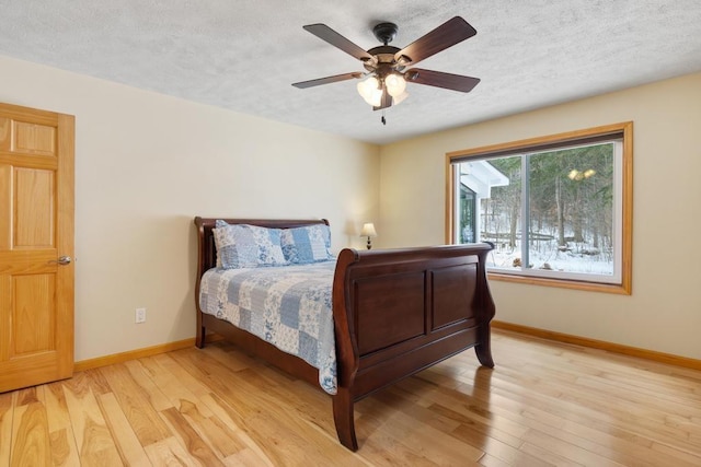 bedroom featuring ceiling fan, light wood-type flooring, and a textured ceiling