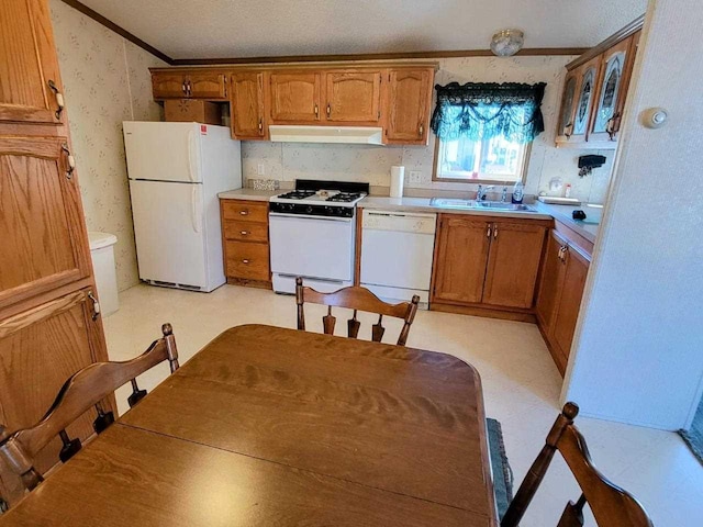 kitchen featuring white appliances, crown molding, and sink