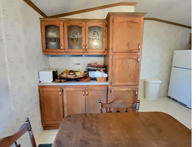 kitchen with ornamental molding, vaulted ceiling, and white refrigerator