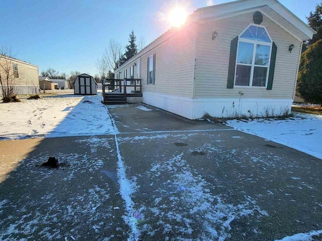 view of snow covered exterior featuring a deck and a storage unit