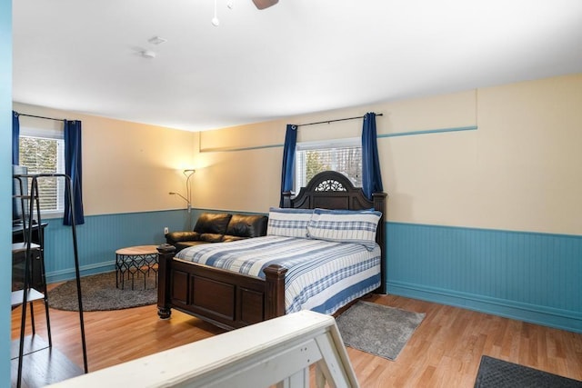 bedroom with ceiling fan, wood-type flooring, and multiple windows