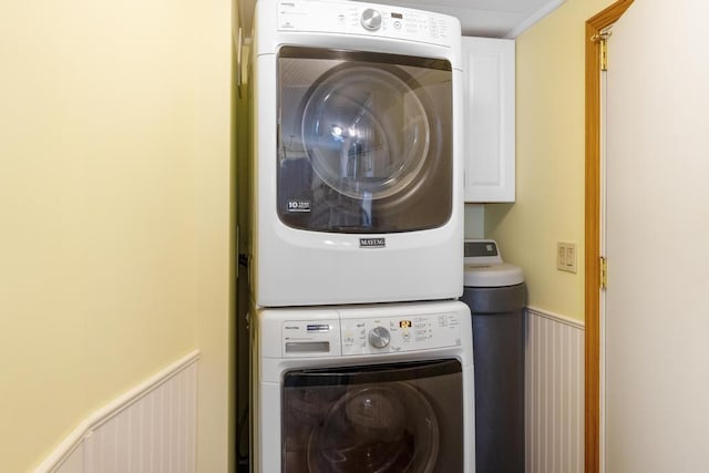 clothes washing area with cabinets and stacked washer and clothes dryer