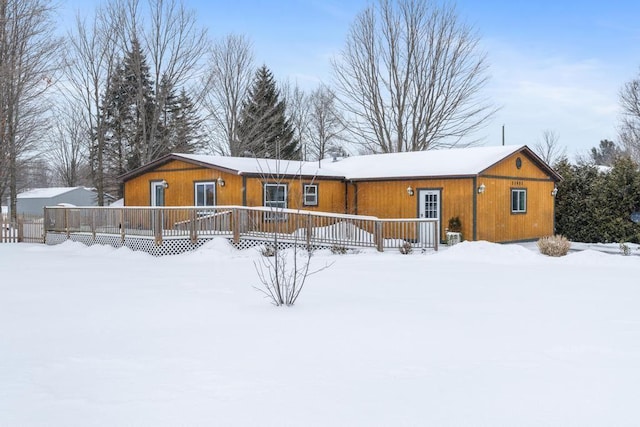 snow covered rear of property with a wooden deck