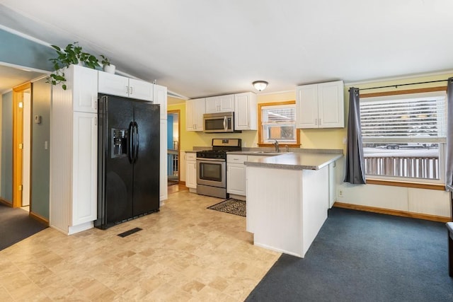 kitchen with kitchen peninsula, appliances with stainless steel finishes, sink, white cabinetry, and lofted ceiling